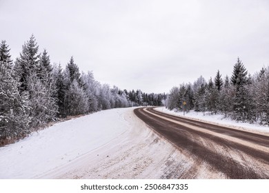 Beautiful view of winding road through snowy forest with frost-covered trees under overcast sky. Sweden. - Powered by Shutterstock