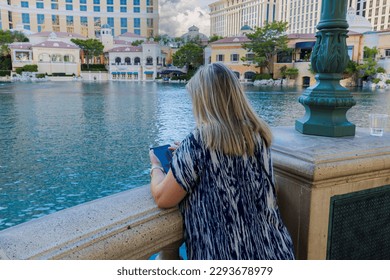 Beautiful view of woman on waterfront of Bellagio hotel surfing on mobile phone. Las Vegas, Nevada, USA.