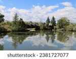 A beautiful view of wooden houses and trees reflected in a lake in the Addenbrooke Park, Lakewood