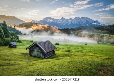 A beautiful view of a wooden hut in the field and the mountains in the background - Shutterstock ID 2051447219