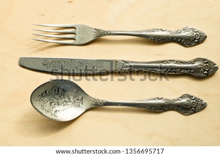 Beautiful vintage cutlery. Silver knive, fork and spoon on the natural wooden background.