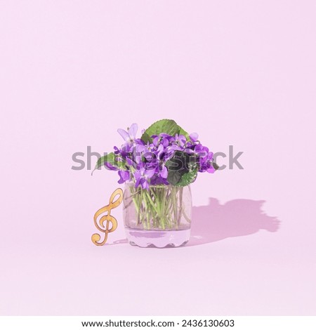 Beautiful violets flowers in a vase and a treble clef . Copy space. Pastel purple background. Front view. Minimal springtime holiday concept. Greeting card.