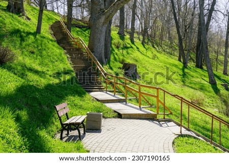 A beautiful walking path with wooden stairs in a nature park in a hilly area, springtime sunlight