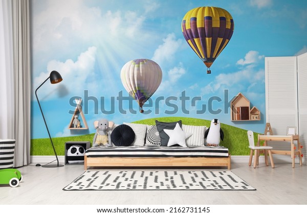 Nice wallpaper with image of hot air balloons in the sky with clouds over green meadow in children's room