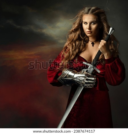 Beautiful Warrior Woman with Sword. Medieval Female Knight in Red Dress with Armor Glove. Beautiful Viking Girl in Fantasy Gown over Dark Sky Background