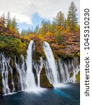 Beautiful waterfall in autumn with green and yellow trees at the top, taken in the middle of October at McArthur-Burney Falls Memorial State Park, in Shasta County, Northern California.