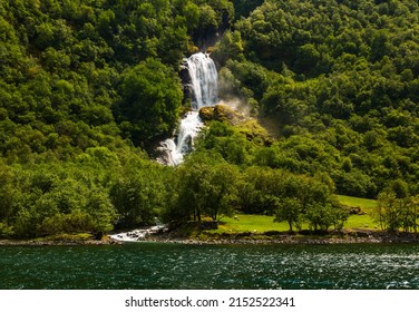 Beautiful Waterfall Between Green Trees On Nærøyfjord In Early Summer In Norway