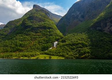 Beautiful Waterfall Between Green Trees On Nærøyfjord In Early Summer In Norway