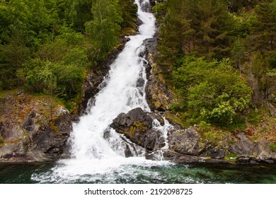 Beautiful Waterfall Between Green Trees On Nærøyfjord In Early Summer In Norway