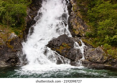 Beautiful Waterfall Between Green Trees On Nærøyfjord In Early Summer In Norway