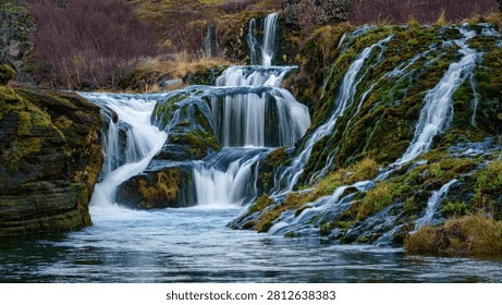 A beautiful waterfall cascading down mossy rocks in a vibrant forest setting.