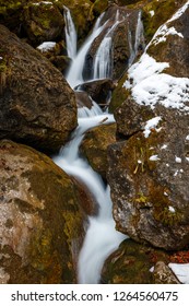 beautiful waterfall in lower Austria shot on a cold winter afternoon with a bit of ice on the sides and green moss growing on logs and rocks