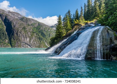 A beautiful waterfall pours massive amounts of water into the sea along Tracy Arm Fjord in Alaska.