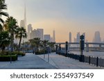  Beautiful waterfront promenade in Dubai Design District with a hazy sunset over Dubai skyline and Burj Khalifa