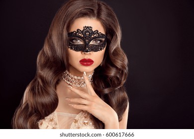 Beautiful wavy hair. Beauty Glamour Woman with luxurious long healthy brown hair wearing lace mask. Red lips makeup. Fashion golden diamond jewelry. Elegant lady isolated on black background. - Powered by Shutterstock