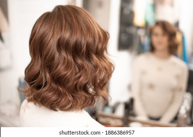 Beautiful Wavy Hair Styling On A Young Woman With Medium Brown Hair Indoors, View From The Back With Reflection In The Mirror, Close-up