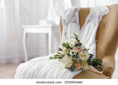 Beautiful wedding bouquet and dress on armchair indoors