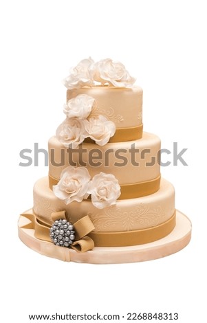 beautiful wedding cake with beige fondant, decorated with cream roses, ribbons and beads. Isolated on white