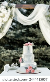 a beautiful wedding cake near the wedding arch in the evening