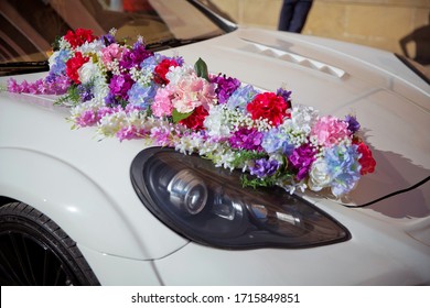Beautiful wedding car. Front of the luxury car decorated flowers . Decorated with flowers as for a wedding . Fresh flowers on the car. Beautiful colorfull wedding bouquet on white wedding car