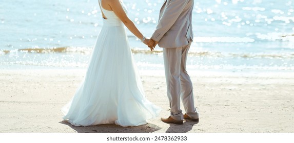 Beautiful wedding couple, bride and groom holding hands on sunny sea coast background - Powered by Shutterstock