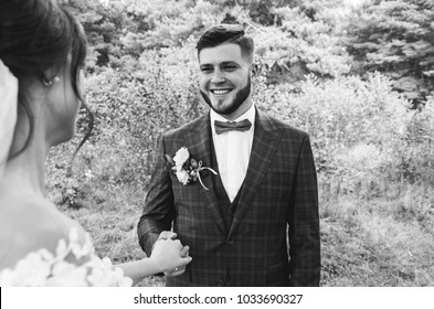 Beautiful Wedding Couple In The Forest. Handsome Bearded Groom With Bow Tie And Checkered Suit In Great Gatsby Style Is Smiling To The Bride. Stylish And Rustic Outdoors Love Story. Black And White