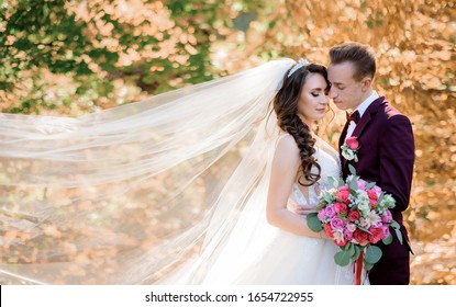 Beautiful wedding couple in the forest with yellowed trees almost kissing, marriage concept, wedding couple in autumn forest