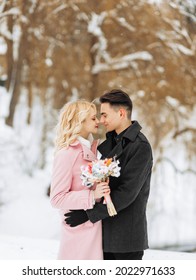 Beautiful wedding couple looks at each other in the woods in winter