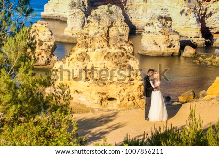 Beautiful wedding couple posing near rocks at beach