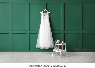 Beautiful wedding dress on green wall with ring box, wedding shoes and bridal bouquet on white wooden stepladder - Powered by Shutterstock