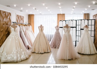 Beautiful Wedding Dresses, Bridal Dress Hanging On Hangers And Mannequins In Studio, Shop. Fashion Look. Interior Of Bridal Salon. Wedding Show Room Trendy, Modern.