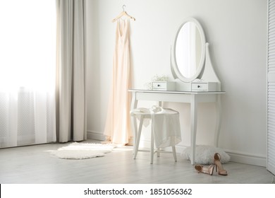 Beautiful Wedding Gown Hanging Near Dressing Table In Room