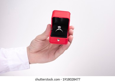 Beautiful Wedding Ring In A Red Box, Man's Hand Offers A Wedding Ring, Cropped Image, Closeup, White Background, Copy Space