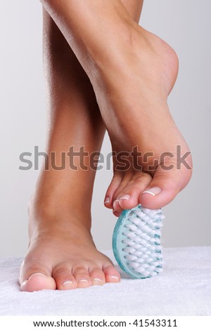Beautiful well-groomed feet, stops of the young woman and pedicure cleaning brush