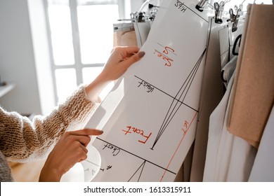 Beautiful well-groomed female hands hold a pattern hanging on a hanger for making a new dress for a project. Dressmaker designer seamstress tailor profession. Layout layout of the shoulders, waist.