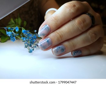 beautiful well  groomed female hands and trendy coating gradient the nails  gel polish bottle blue color  design in the style minimalism marble  airy effect