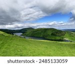 Beautiful Welsh rural landscape and lake. Summer time, green grass and blue sky. Holiday in the countryside next to the river. Natural green background.