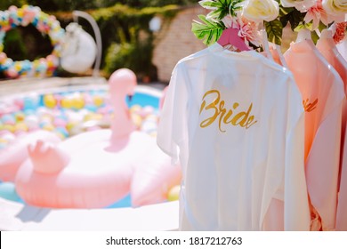 Beautiful white bathrobes for the bride and her bridesmaids hanging in the yard at a bachelorette party
