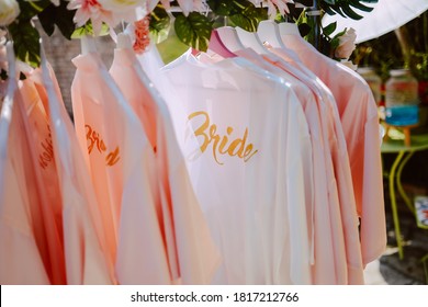 Beautiful white bathrobes for the bride and her bridesmaids hanging in the yard at a bachelorette party

