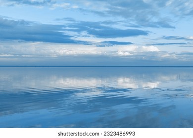 Beautiful white blue clouds over lake, symmetric sky background, cloudscape on lake Ik, Russia. Nature abstract, cloudy sky reflected on water, calm windless weather, natural environment, skyline