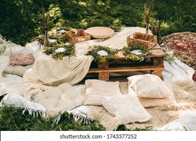 Beautiful white decor in boho style. Picnic in nature, table, carpets, wigwam, tent, pillows in the park. Celebration after quarantine. - Powered by Shutterstock