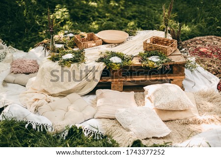 Beautiful white decor in boho style. Picnic in nature, table, carpets, wigwam, tent, pillows in the park. Celebration after quarantine.