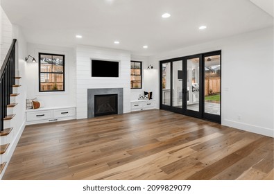 Beautiful White Farmhouse Style Living Room In New Luxury Home. Features Hardwood Floors, White Shiplap, Fireplace, And Sliding Glass Doors Leading To Covered Patio With Fireplace And Tv.