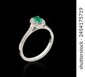 Beautiful white gold ring with diamonds and emerald on a black background close-up