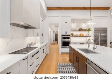 Beautiful white kitchen in new luxury home with large island. Features large island, stainless steel appliances, and sleek modern range hood. - Powered by Shutterstock