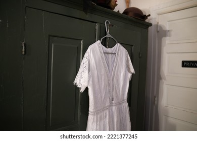 A Beautiful White Lace Dress Hanging From A Closet In A Room