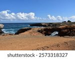 Beautiful white low clouds over deep blue ocean waters off lava rock bluff.