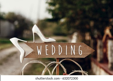 Beautiful White Shoes On Wooden Arrow With Wedding Text Sign. Rustic Wedding Concept. Pointing For Wedding Ceremony Location. Creative Ideas