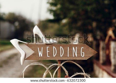 beautiful white shoes on wooden arrow with wedding text sign. rustic wedding concept. pointing for wedding ceremony location. creative ideas