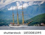 Beautiful white vintage sailboat, ship with three masts, barque, brig, floating in the sea on the background of mountains